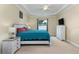 Bright bedroom with a tray ceiling, window with curtains, TV on a dresser, and a bed with a white wood frame at 420 Tulipwood Ln, Chuluota, FL 32766