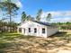 Exterior of modern home with white stucco, dark roof, and a spacious yard surrounded by trees at 6106 Sw 127 Avenue Rd, Ocala, FL 34481