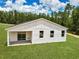 Rear exterior view of home with backyard lawn and partially covered patio area at 6106 Sw 127 Avenue Rd, Ocala, FL 34481