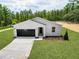 Charming house showcasing a driveway, lush lawn, and dark garage door at 6106 Sw 127 Avenue Rd, Ocala, FL 34481