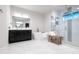 Bright bathroom with a soaking tub, glass shower, black cabinets, and white marble-style tile floor at 7065 Branch Court, St Cloud, FL 34771