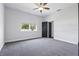 A modern bedroom with neutral gray tones has a large window and ceiling fan at 7065 Branch Court, St Cloud, FL 34771
