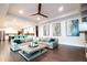 Open-concept living room with a large gray sofa, wood floors, modern ceiling fan, and view into the kitchen at 7065 Branch Court, St Cloud, FL 34771