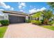 Charming single-story home with a well-manicured lawn, mature landscaping, and a brick paver driveway at 8137 Pond Apple Dr, Winter Garden, FL 34787