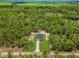 An aerial view of a modern home nestled in lush greenery with a long driveway, offering privacy and serenity at 8258 Sw 136Th Ter, Dunnellon, FL 34432