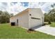 Exterior view of a home featuring white siding, a two-car garage, and lush landscaping at 8258 Sw 136Th Ter, Dunnellon, FL 34432