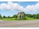 Beautiful community entrance with stone sign, manicured lawn, and lush trees at 9389 Meadow Hunt Way, Winter Garden, FL 34787