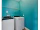 Efficient laundry room with a vibrant turquoise wall, washer, dryer, and convenient shelving for storage at 9389 Meadow Hunt Way, Winter Garden, FL 34787