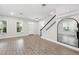 Bright living room with large windows, wood-look flooring, staircase, and an arched mirror reflecting the open space at 9389 Meadow Hunt Way, Winter Garden, FL 34787