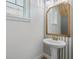 Chic powder room with a pedestal sink, decorative mirror, and stylish striped wallpaper at 9389 Meadow Hunt Way, Winter Garden, FL 34787