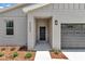 Charming single-Gathering home front entrance with a black front door and a gray garage door at 9695 Sw 125 Court Rd, Dunnellon, FL 34432