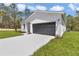 Charming home featuring white board and batten siding, a gray garage door, and a pristine concrete driveway at 12197 Sw 76 Ln, Dunnellon, FL 34432