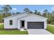 A simple home displays an inviting entrance, modern gray garage door, and a verdant front lawn at 12197 Sw 76 Ln, Dunnellon, FL 34432
