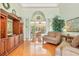 Elegant living room with hardwood floors, built-in shelving, and large windows overlooking a serene outdoor space at 13524 Glynshel Dr, Winter Garden, FL 34787