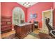Comfortable home office featuring a large arched window and a classic wood desk with leather chair at 13524 Glynshel Dr, Winter Garden, FL 34787