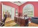 Home office with a large arched window, wood desk and leather chair, adjacent to the dining room at 13524 Glynshel Dr, Winter Garden, FL 34787