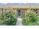 Front door with green bushes and foliage alongside a concrete walkway leading to the house's entrance at 1387 Sawgrass Court, Winter Park, FL 32792