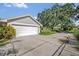 Spacious two-car garage with a concrete driveway and a large tree providing shade in the yard at 1387 Sawgrass Court, Winter Park, FL 32792