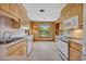 Well-lit kitchen features wood cabinetry, white appliances, and a large window with scenic outdoor views at 1387 Sawgrass Court, Winter Park, FL 32792