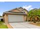 Beige single Gathering home with a concrete driveway leading to a two car garage and tropical landscaping at 14617 Keelford Way, Orlando, FL 32824