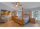 Charming bedroom with a wooden canopy bed, light fixture and a comfortable sitting area at 14651 Pine Cone Trl, Clermont, FL 34711