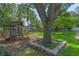 Outdoor play area with playhouse, slide, and tree, surrounded by lush greenery at 14651 Pine Cone Trl, Clermont, FL 34711