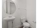 Modern half-bathroom featuring a pedestal sink, toilet, round mirror, and neutral wall color at 15161 Lake Bessie Loop, Winter Garden, FL 34787