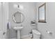 Powder room with pedestal sink, stylish mirror, and modern toilet design at 15698 Panther Lake Dr, Winter Garden, FL 34787