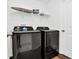 Modern laundry room with dark front-load washer and dryer, a storage shelf, and a white door at 1615 Sanibel Dr, Davenport, FL 33896