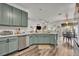 A kitchen has stainless steel appliances and muted green cabinets, open to the living and dining areas at 2039 Beachberry Ln, Oviedo, FL 32765