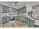 A stylish kitchen features stainless steel appliances and muted green cabinetry with quartz countertops at 2039 Beachberry Ln, Oviedo, FL 32765
