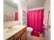 Well-lit bathroom featuring a vanity, toilet, and shower with a colorful pink curtain at 212 Ashford Dr, Davenport, FL 33837