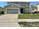 Two-story home featuring an attached two-car garage and a young palm tree in the front yard at 235 Hibiscus St, Winter Haven, FL 33881