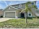Two-story home featuring an attached two-car garage and a small palm tree in the front yard at 235 Hibiscus St, Winter Haven, FL 33881