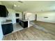 Open living room with wood floors, island with double sinks, and modern black cabinets at 235 Hibiscus St, Winter Haven, FL 33881