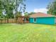 Turquoise home exterior with a wooden patio and covered deck in the lawn at 2545 El Portal Ave, Sanford, FL 32773