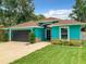 Charming turquoise home featuring a well-kept lawn, a dark grey garage door, and a cozy front porch at 2545 El Portal Ave, Sanford, FL 32773