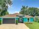 Charming turquoise home featuring a well-kept lawn, a dark grey garage door, and a cozy front porch at 2545 El Portal Ave, Sanford, FL 32773