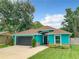 Charming turquoise home featuring a well-kept lawn, a dark grey garage door, and a cozy front porch at 2545 El Portal Ave, Sanford, FL 32773