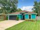 Charming turquoise home featuring a well-kept lawn, a dark grey garage door, and a cozy front porch at 2545 El Portal Ave, Sanford, FL 32773