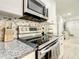 Close-up of stainless steel oven and mosaic backsplash in a well-equipped kitchen featuring granite counters and white cabinets at 2545 El Portal Ave, Sanford, FL 32773