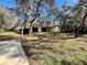 Back view of home with covered patio and large yard shaded by mature trees at 285 W 2Nd St, Chuluota, FL 32766
