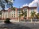 Exterior view of the Galleria Palms Hotel showcases architectural details, lush greenery and ample parking at 3000 Maingate Ln # 210, Kissimmee, FL 34747
