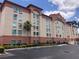 Exterior view of the hotel with neutral colors and a palm tree in front of the building at 3000 Maingate Ln # 210, Kissimmee, FL 34747