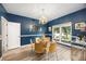 Chic dining room featuring blue walls, wood floors, glass table, and elegant chandelier at 383 Remington Dr, Oviedo, FL 32765