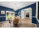 Elegant dining room boasts blue walls, wood floors, a glass table, and views of the front yard at 383 Remington Dr, Oviedo, FL 32765