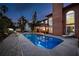 An illuminated backyard pool at twilight, surrounded by lush greenery, covered patio and outdoor seating at 383 Remington Dr, Oviedo, FL 32765