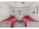 Cozy bedroom with two twin beds, bright red accents, and a window with natural light at 6057 Lake Pointe Dr # 408, Orlando, FL 32822
