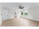 Bright bedroom with light wood floors, a ceiling fan, and large windows overlooking lush trees at 7085 Willowwood St, Orlando, FL 32818