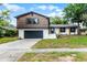 Two-story home with brown siding, white painted brick, an attached garage, and freshly landscaped yard at 7085 Willowwood St, Orlando, FL 32818